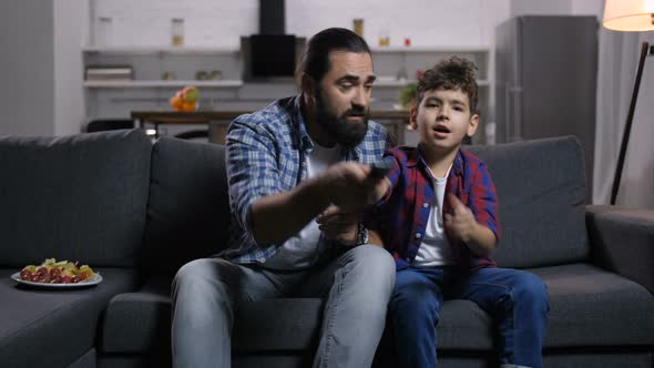 Handsome Dad and Son Fighting for Tv Remote Control