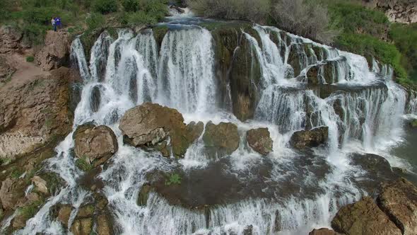 Flying view of waterfall flowing over edge into river