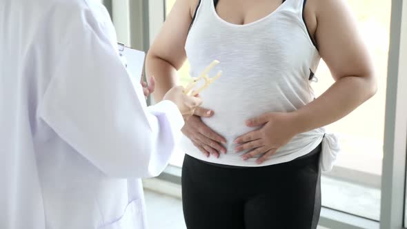 Doctor measuring fat layer of overweight woman with caliper in clinic