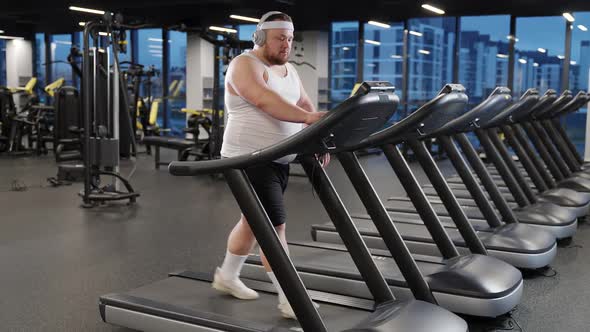 Excess Weight Overweight Man Run on a Treadmill and Listening to Music with Headphones Aerobic