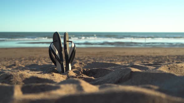 Sandals in the beach sand on summer holiday sunny day, shallow depth of field