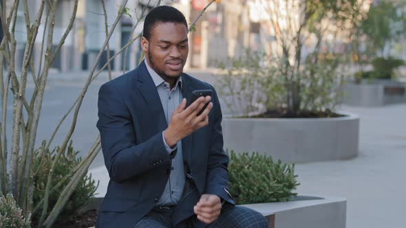 Irate Annoyed Angry African American Black Businessman Holding Smartphone Looking at Phone Screen