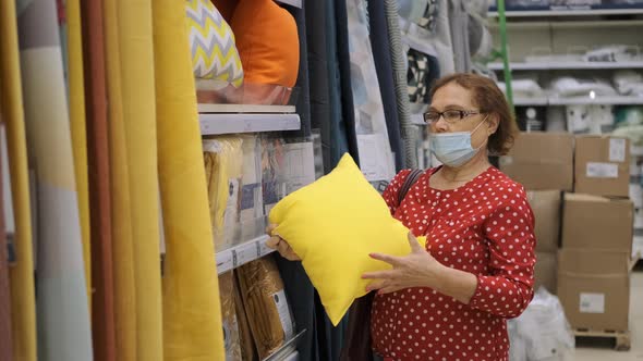 Senior Female in Protective Mask Buying Pillow