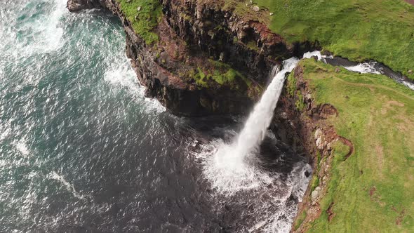 Stunning Waterfall Splashing From Cliff Aerial View. Mulafossur Waterfall Near Gasadalur Village at