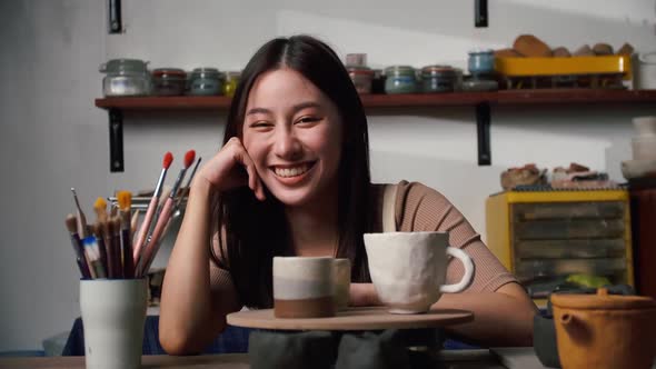 A female ceramicist is creating a new pottery in the workshop. Asian woman is enjoying pottery work.