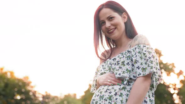 Pregnant Caucasian Woman in Summer Dress Posing Outdoors