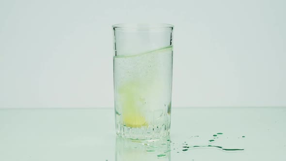 Close-up Shot of An Effervescent Tablet Against Pain Falls Into a Glass and Dissolves Slow-motion