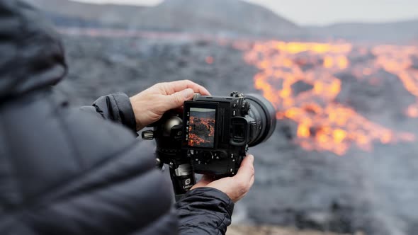 Photographer Adjusting Camera On Tripod With Lava Flow