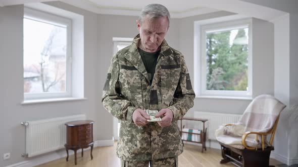 Middle Shot Portrait of Sad Middle Aged Soldier Holding Money and Thinking
