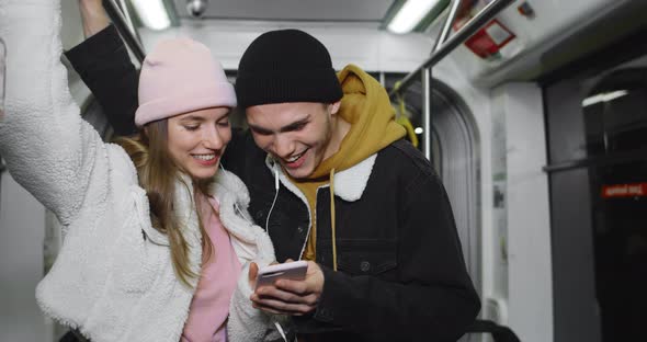 Young Guy and His Girlfriend Using Smartphone and Laughing While Looking at screen.Cheerful Couple