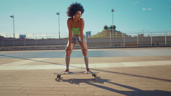 Beautiful young woman cruising around the city with her longboard.
