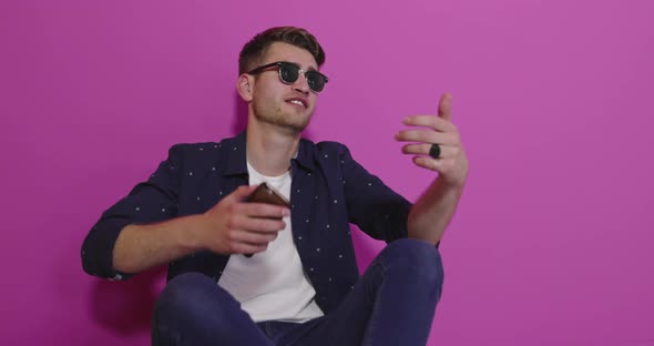 Portrait of a Happy Man Using Mobile Phone Isolated Over Pink Background