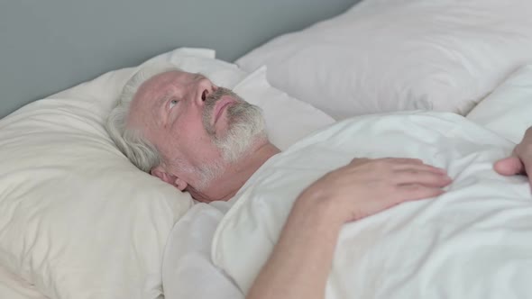 Pensive Old Man Laying in Bed Thinking