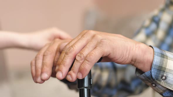 Close-up of a child stroking the hands of an old man holding a walking stick.The grandson communicat