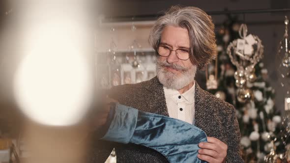 Mature Man Holding Blue Stocking Standing with Grandson in a Shop