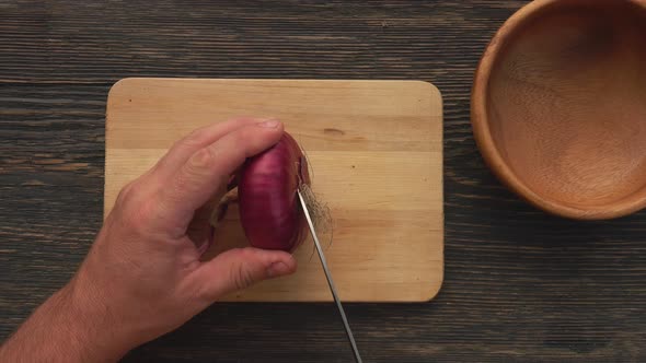 Top View of the Male Hands Cutting Red Onion Rings on the Wooden Board