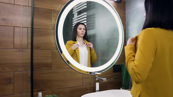 Woman in Stylish Suit which Standing Near the Mirror Straightening Her Clothes and Hairstyle