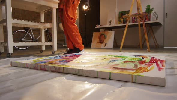 Low section of african american male artist pouring paint on canvas at art studio