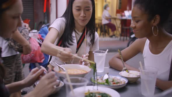 A group of multi-ethnic female friends enjoying street food on Yaowarat Road or Chinatown in Bangkok