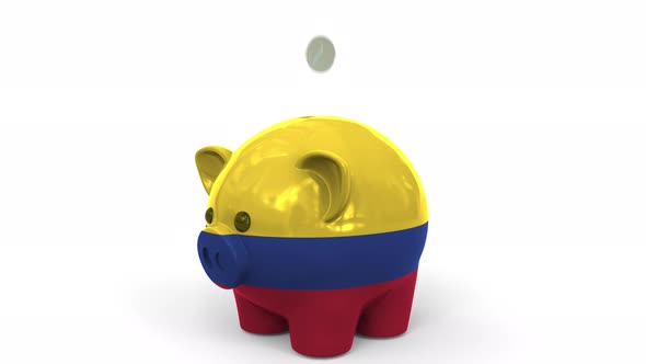 Coins Fall Into Piggy Bank Painted with Flag of Colombia alt