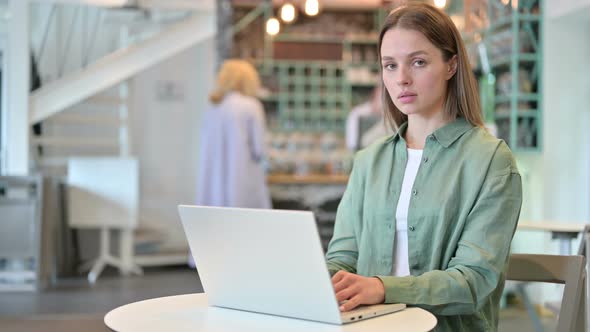 Serious Woman with Laptop Looking at Camera