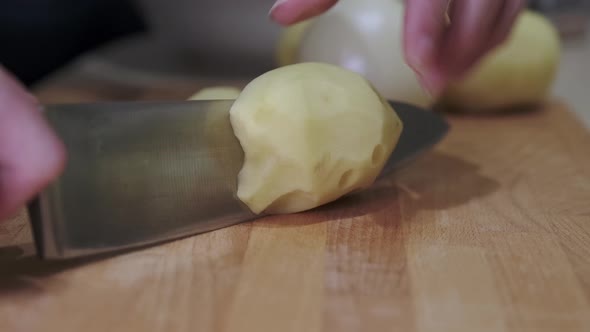 The cook cuts raw potatoes into pieces. Cooking fried potatoes at home.