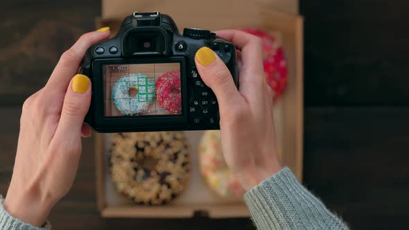 Woman's Hands Take Pictures with Photo Camera of Delicious Donuts in Box