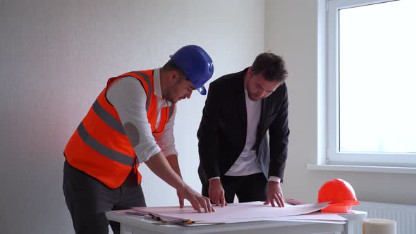 Two Men Architect and Engineer in Casual Clothes and Architect in Vest and Hardhat Working with