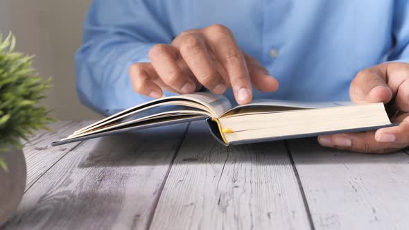 Muslim Man's Hand Reading Quran on Table 