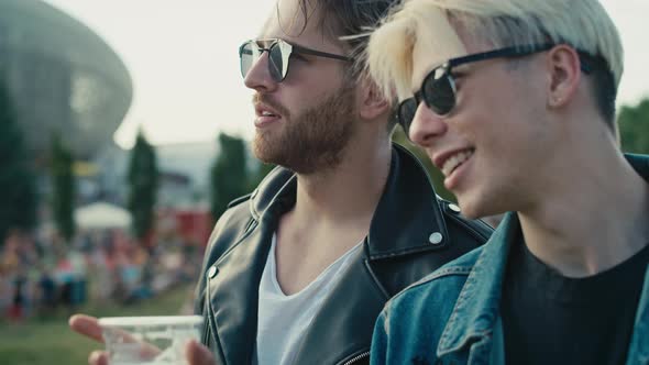 Two young caucasian men having fun on music festival while drinking beer. Shot with RED helium camer