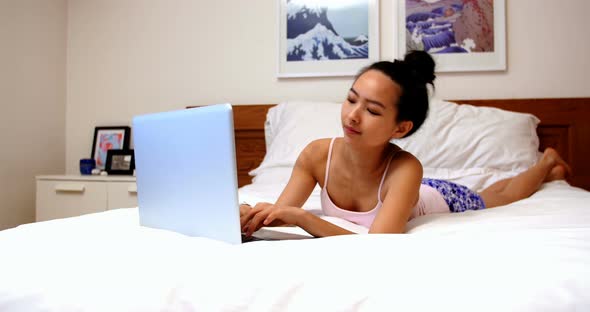 Beautiful woman relaxing on bed and using laptop