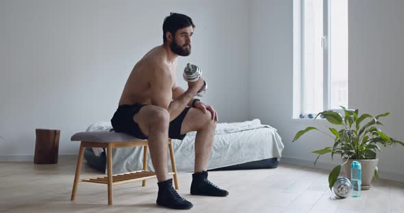 Young Man with Naked Torso Lifting Dumbbell at Home