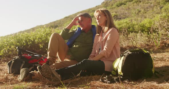 Active senior couple sitting on the floor in forest