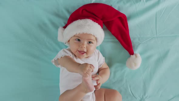 Funny Little Baby Smiling of the 2021 Year. Cute Infant Boy Wearing Santa Hat Lying on Sofa.