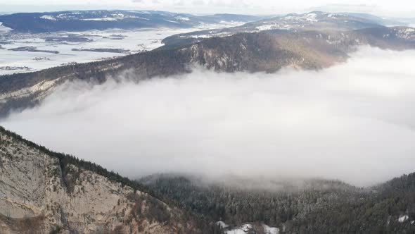 Aerial of low hanging clouds in snow covered mountain pass