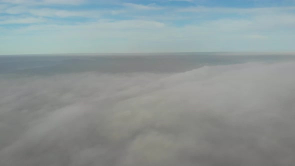 Flying over clouds. Video shot by drone in early morning. Smog above city.