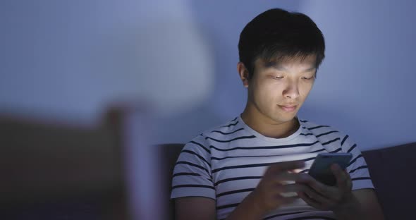 Man playing mobile game on cellphone at night