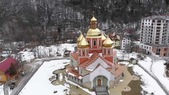 Aerial View of Ukrainian Church with Golden Domes in Carpathian Village in Winter