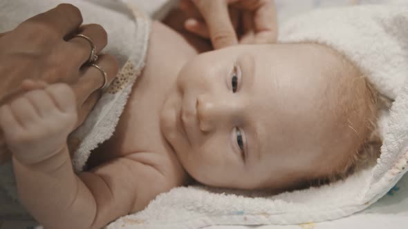 A Little Baby Lying in Bed and His Mother Wiping Out His Face Before Sleep