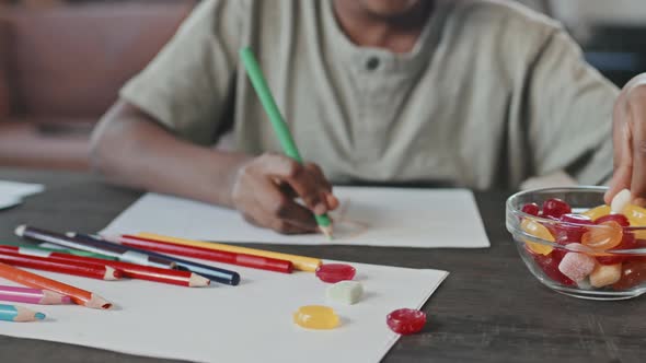 Kid Drawing and Eating Candies