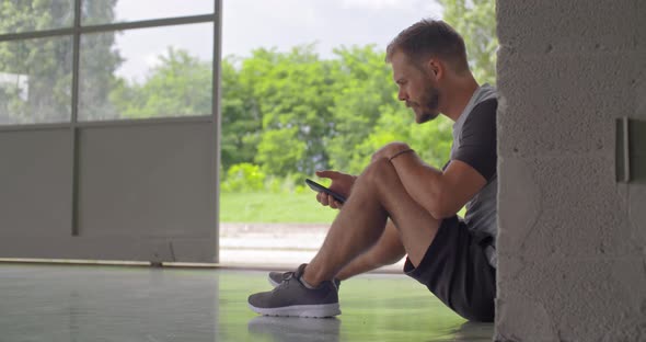 Young Adult Man Using Smartphone Tracking App During Fitness Sport Workout