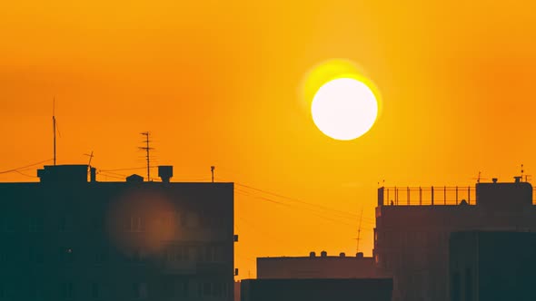 A timelapse of sunrise in the city. Close-up of the yellow sun rising over the apartment buildings