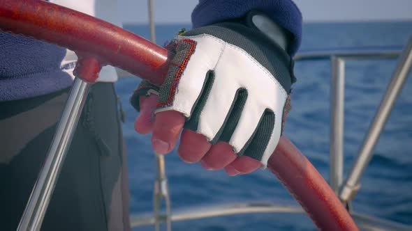 Extreme close up of sailor controlling the direction of sailboat with steering wheel.