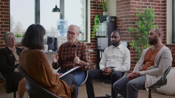 Senior Man Making Confession in Front of People at Aa Group Therapy Session