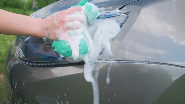 A person washes the car with water and foam.