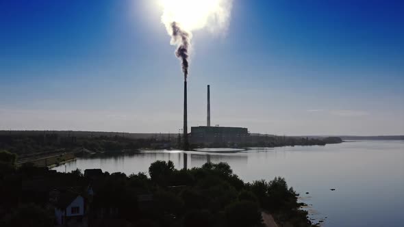 Industrial zone with large pipes. Thick white smoke is pouring in contrast to the sun. 