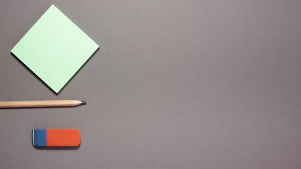 Wooden pen,, sticky note and eraster on gray background. Stop motion animation flat lay top view alt