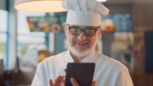 Portrait of Mature Male Chef Using Digital Tablet in Modern Fast Food Cafe