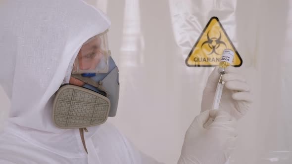 Doctor in a Medical Protective Suit Holding a Coronavirus Vaccine and a Syringe