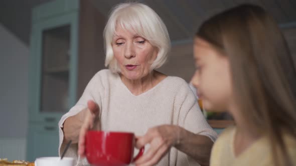 Happy grandmother and granddaughter having breakfast